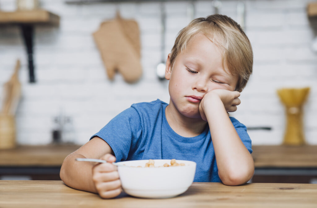 front view tired boy trying eat his cereals
